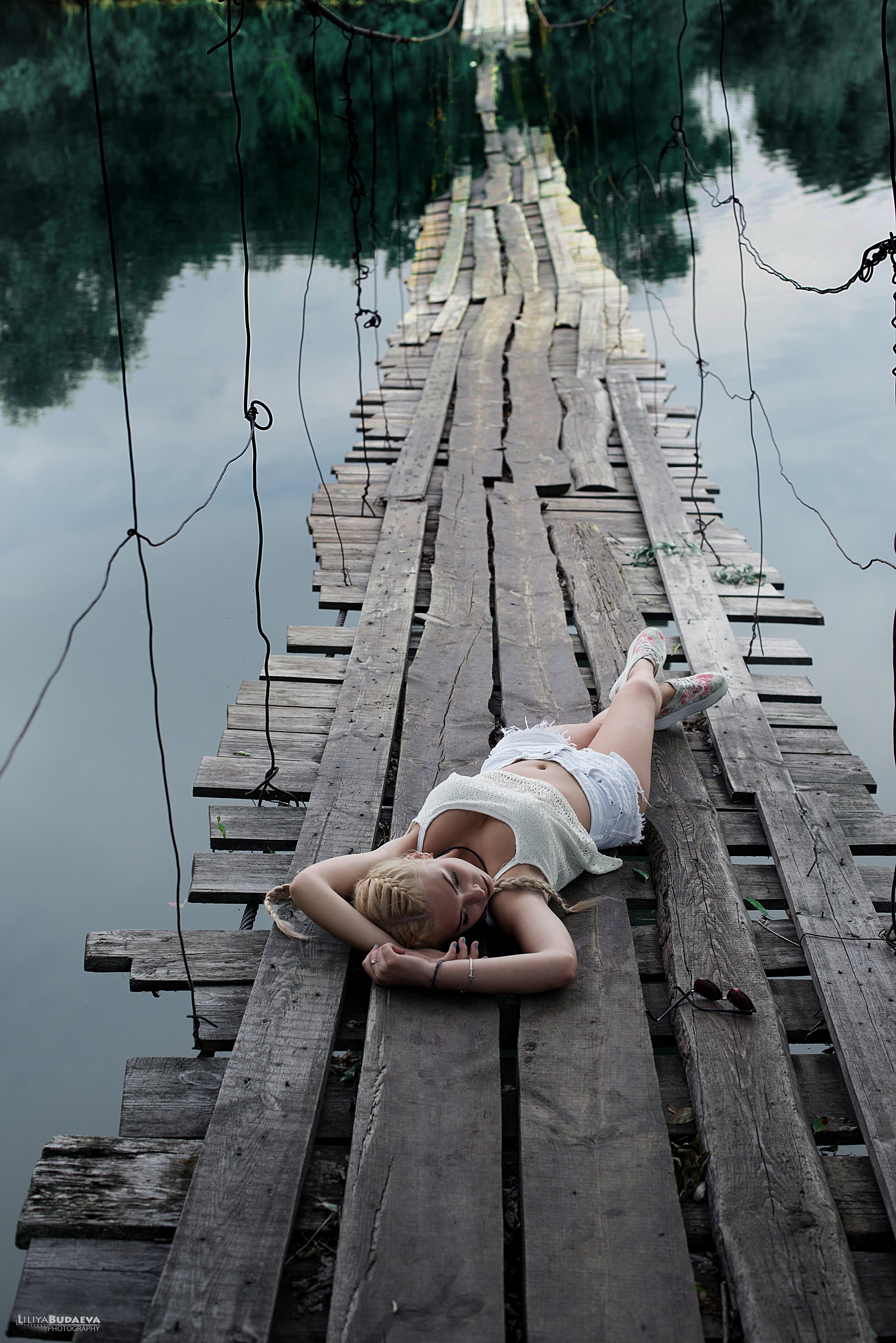 Стройная пожилая женщина голая на деревянном мосту 